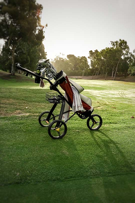 Fotografía de un carro de gol sobre un campo de golf en un atardecer